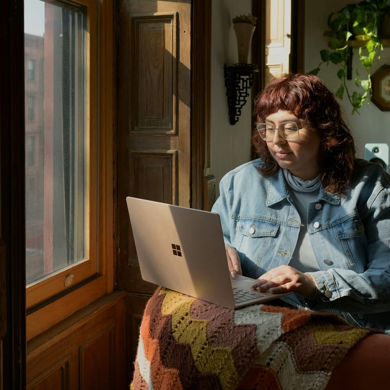 A woman on a sofa using a laptop for an online call